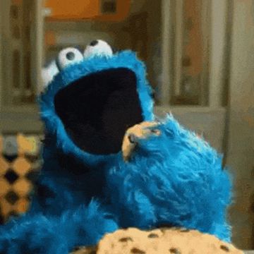 Koekiemonster schrokt een koekje naar binnen, de kruimels vliegen in het rond.